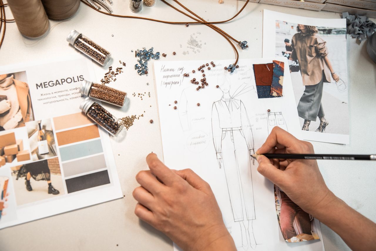 Fashion designer sketching in a workspace with materials and mood boards.